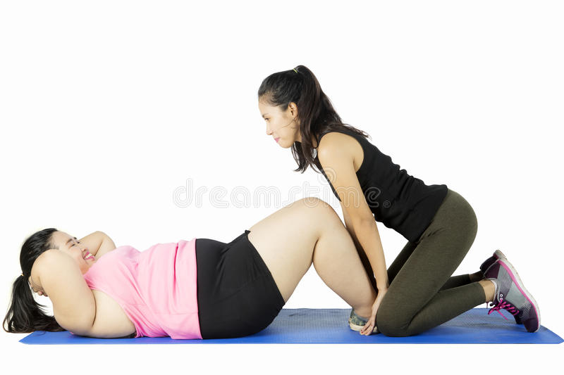 instructor-helping-obese-woman-exercise-young-women-doing-sit-up-mat-isolated-white-background-94609959